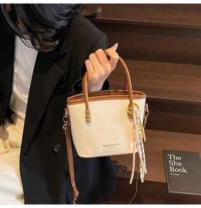 Close-up of contrast color bucket bag showing MIKAXIQI logo and woven charm detail
