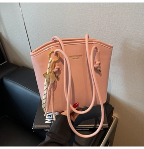 Dettaglio della borsa rosa in pelle con ciondolo a racchetta d'oro e nappa colorata