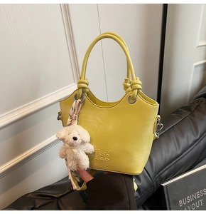 Détail du sac seau en cuir vert citron avec breloque chien et lettrage en relief
