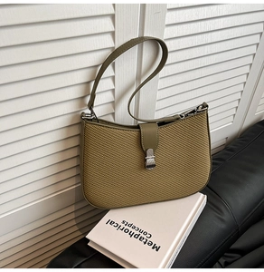 Detailed close-up of olive green woven texture and silver metal hardware on shoulder bag