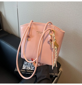 Dettaglio borsa tote in pelle rosa con etichetta logo e cinturino intrecciato