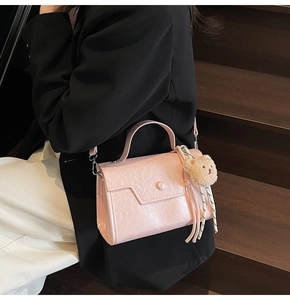 Detail of pink faux leather bag with pleated texture and cute bear charm in use