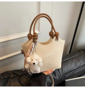 Détail du sac seau crème avec poignée en corde marron et charm de chien blanc