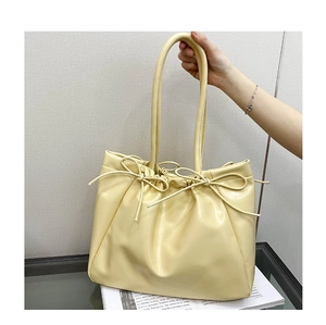 Vue détaillée du grand sac cabas crème en cuir avec nœuds décoratifs sur verre