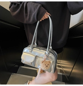 Detail der silbernen Metallic-Tasche mit mehreren Taschen und Bären-Anhänger