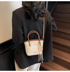 Detail of a cream and brown contrast bucket bag styled with a professional outfit