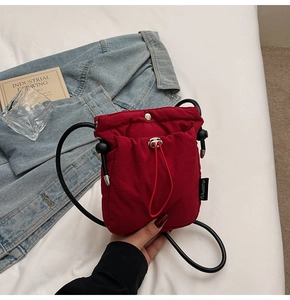 Close-up of red nylon drawstring bucket bag with silver buckle and black rope strap