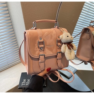 Detailed view of pink PU leather mini backpack with metal buckles and plush bear charm