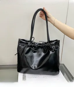 Détail du grand sac cabas noir brillant avec nœuds décoratifs et effet plissé