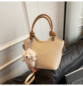 Détail du sac seau beige avec poignée nouée et accessoire charmant de chien en peluche