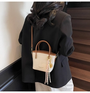 Close-up of contrast color bucket bag with braided knot charm and gold hardware detail