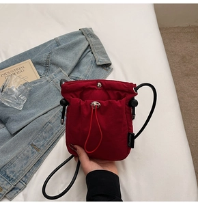 Close-up of red drawstring bucket bag with black brand label on white fabric
