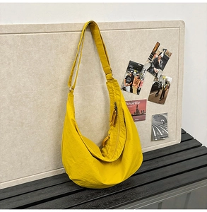 Detailed close-up of yellow crescent hobo bag with adjustable strap in a lifestyle setting