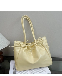 Détail du sac cabas crème en cuir souple avec plis coulissants et nœuds élégants