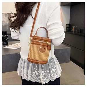 Dettaglio borsa a secchiello cilindrica intrecciata beige e pelle marrone con tracolla