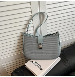 Close-up of the light blue underarm bag featuring a woven texture and silver metal snap