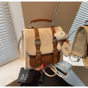 Detail of the cream and brown contrast backpack with bear charm and leather texture