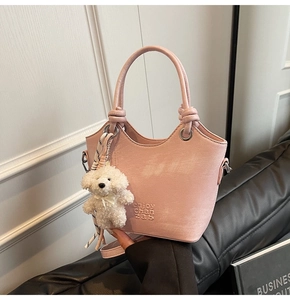 Détail du sac seau rose avec poignée nouée et breloque chiot en peluche blanche douce