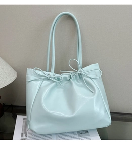 Détail du sac cabas bleu menthe avec nœuds décoratifs et texture simili cuir brillant