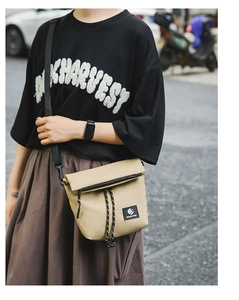 Detailed view of khaki nylon crossbody bag with flap zipper and adjustable strap on a model