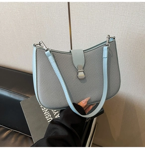 Detailed view of light blue and grey patchwork shoulder bag with woven texture and metal buckle
