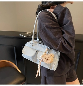 Hellblaue Lackleder-Schultertasche mit Fronttaschen und Plüschbär-Anhänger am Modell
