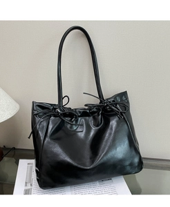 Détail du grand sac cabas noir en cuir avec nœuds décoratifs et fermeture par cordon plissé