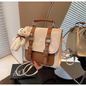 Detailed view of bicolor leather bag featuring fashion text and cute bear charm