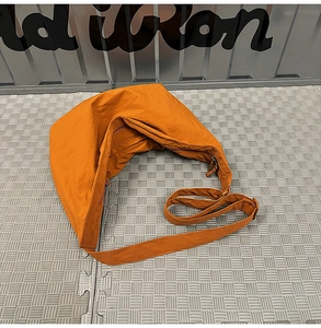 Detailed macro view of orange crescent bag made of water-resistant nylon with wide strap
