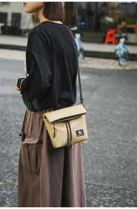 Outdoor shot of khaki nylon messenger bag with drawstring detail and logo patch