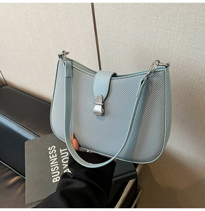 Close-up of the light blue twill fabric texture and silver metal lock on the saddle bag