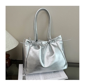 Détail du sac cabas en similicuir argenté avec un nœud décoratif et une finition métallique