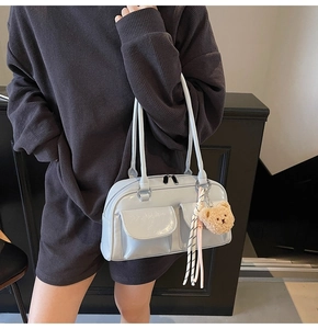 Detail der hellblauen glänzenden Handtasche mit Klapptaschen und Plüschbär-Anhänger