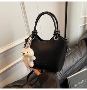 Détail du sac seau noir avec œillets argentés et porte-clés ours blanc en peluche