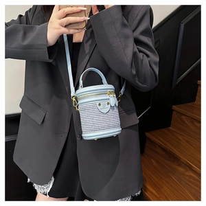 Dettaglio della borsa cilindrica intrecciata azzurra con finiture in pelle e oro