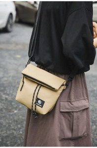 Detail of khaki nylon messenger bag showing drawstring closure and SHILAEN STUDIO logo