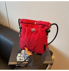 Detail of red nylon drawstring bucket bag with silver hardware and black rope strap