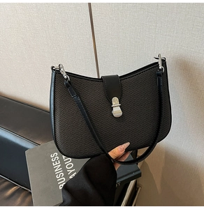 Detail of black herringbone fabric shoulder bag with sleek leather trim and silver buckle