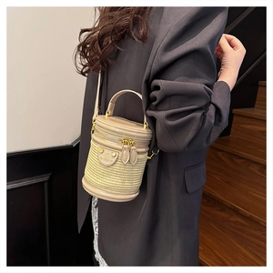 Dettaglio di una borsa cilindrica in pelle beige e intreccio con zip dorata di lusso
