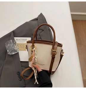 Detail of contrast bucket bag with leather handles and decorative woven rope charm
