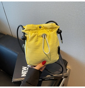 Close-up of bright yellow nylon bucket bag with drawstring and silver hardware