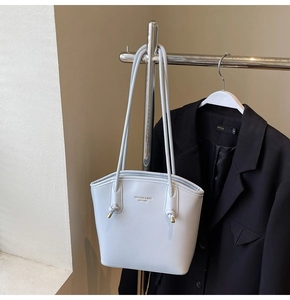 Dettaglio della borsa tote azzurra minimalista con finiture dorate e tracolla annodata