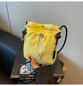 Detail of bright yellow nylon mini bucket bag with drawstring closure and slim rope strap