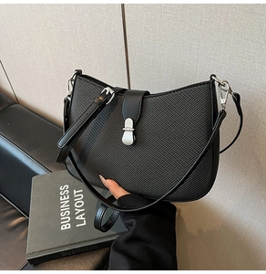Detail of black crescent shoulder bag with textured woven pattern and silver metal buckle