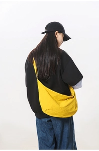 Detail of bright yellow crescent bag on model showing large capacity and nylon texture