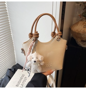 Détail du sac seau crème avec poignées marron et charmant pendentif chiot en peluche