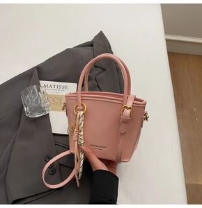 Detail showing pink leather bucket bag with silk scarf and gold metal hardware