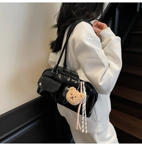 Detail der schwarzen Lackleder-Schultertasche mit Frontklappentaschen und Bärenanhänger