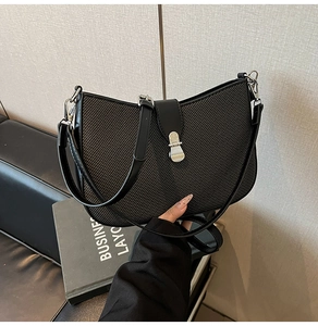 Close-up of black crossbody bag with twill texture and silver metallic clasp detail