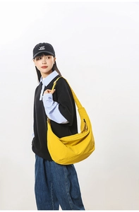 Detail of yellow nylon dumpling bag with black zipper and wide shoulder strap
